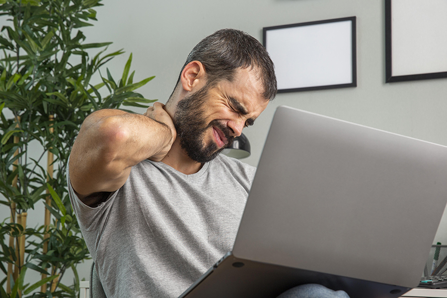 man-experiencing-neck-pain-while-working-from-home-laptop