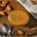 کره بادام‌زمینی روی تخته چوبی با بادام خام – آیا چاق‌کننده است؟
