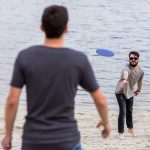 2 جوان در حال بازی با فریزبی کنار دریا با فریزبی تن زیب مدل بشقابی