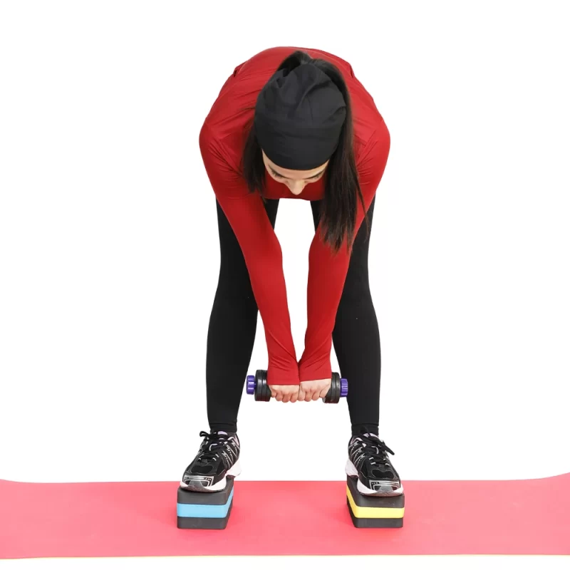 دختر ورزشکاری با لباس قرمز در حال تمرین دمبل تن زیب با قابلیت تغییر وزن و آجرهای یوگا