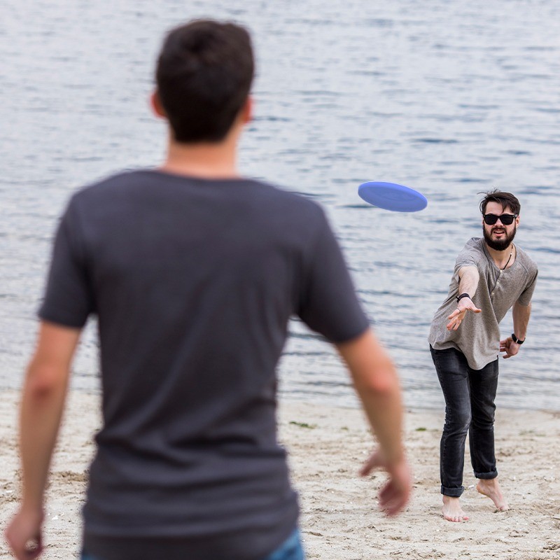 2 جوان در حال بازی با فریزبی کنار دریا با فریزبی تن زیب مدل پره ای