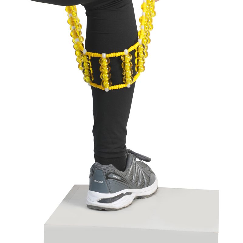 ماساژور کمر تن‌زیب مدل مهره‌ای زرد روی ساق پای فرد با کفش طوسی و شلوار مشکی