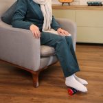ماساژور رولی کف پا تن‌زیب مدل چرخ‌دنده‌ای زیر پای خانمی در فضای داخلی